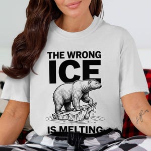Puede incluir: Camiseta blanca con un diseño gráfico en blanco y negro de un oso polar sobre un témpano de hielo derritiéndose. El texto "THE WRONG ICE IS MELTING" está impreso. La camiseta es de estilo casual.