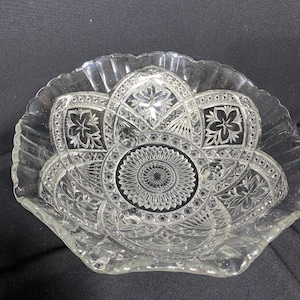以下が含まれることがあります： 花柄と幾何学模様の透明なガラス製サービングボウル。ボウルはスカラップエッジと中央にスターバーストデザインがあります。ボウルはおそらくヴィンテージで、サラダやフルーツのサービングに適しています。