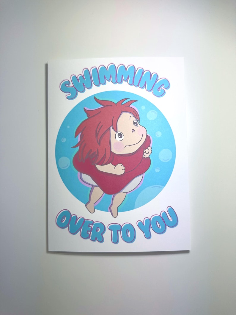 K&ouml;nnte beinhalten: Wei&szlig;e Gru&szlig;karte mit einer Cartoon-Illustration einer Figur mit roten Haaren und einem roten Kleid, die in einem blauen Kreis schwimmt. Die Worte "SWIMMING OVER TO YOU" sind in blauen Buchstaben geschrieben.