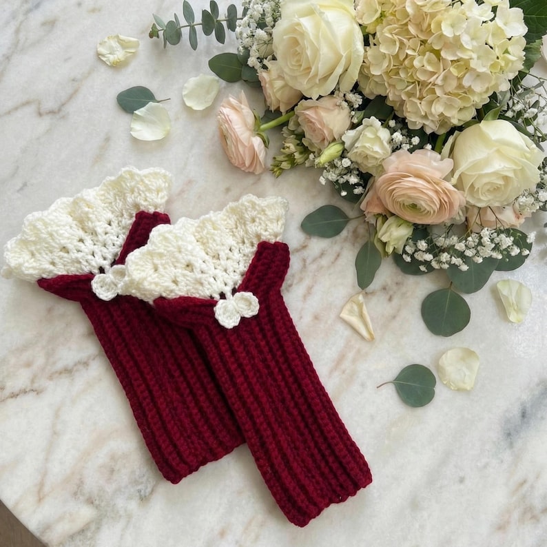 Red and cream lace wrist warmers on a marble background, perfect for cottagecore crochet lovers.
