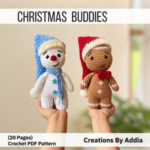 May include: Two crocheted dolls titled CHRISTMAS BUDDIES. One is a white snowman with a blue hat and scarf, the other is a brown gingerbread person with a red hat and bow tie. The text reads (20 Pages) Crochet PDF Pattern and Creations By Addia.