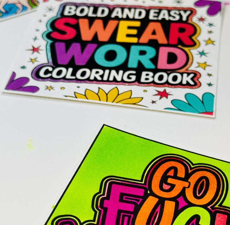 May include: A colorful coloring book with the title "Bold and Easy Swear Word Coloring Book". The cover features a rainbow-colored font and a variety of colorful stars and flowers.
