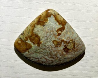 May include: A polished, triangular gemstone with a mix of brown, tan, and pale green hues. The stone has a marbled appearance with intricate patterns and a smooth, glossy finish. The edges are rounded, and the overall shape is symmetrical.