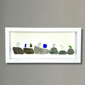 May include: A framed artwork featuring a row of small, colorful birds made from sea glass and stones. The birds are perched on individual stones, creating a whimsical and charming scene.