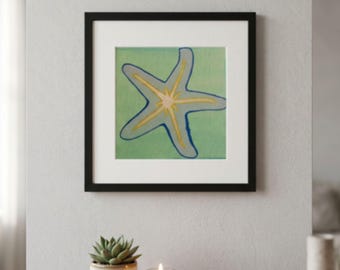 May include: A square framed wall art piece featuring a stylized starfish illustration. The starfish is rendered in shades of light blue and yellow against a solid light green background. The artwork is enclosed in a simple black frame with a white mat.