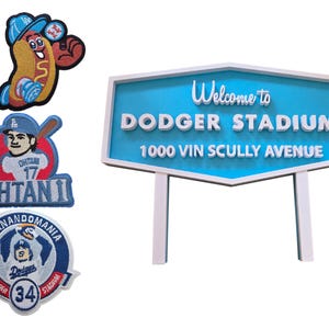 Può includere: Una collezione di toppe a tema baseball e un cartello. Le toppe includono un hot dog con un cappello da baseball, un giocatore con il nome "Ohtani 17" e una toppa "Fernandomania". Il cartello recita "Welcome to Dodger Stadium".