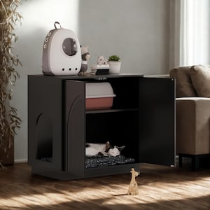 May include: A black cat house with an open door, revealing a sleeping cat on a patterned mat. The cabinet has a top shelf with a cat carrier, figurines, and a small potted plant. A litter box is visible inside.
