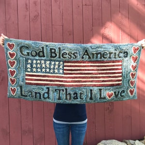 May include: A blue and red hooked rug with the words "God Bless America Land That I Love" and a depiction of the American flag.