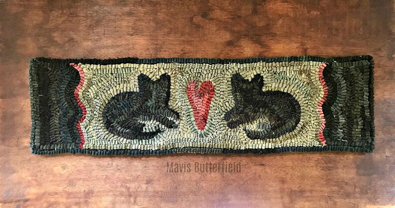 May include: A black and white hooked rug with two black cats and a red heart in the center. The rug has a scalloped edge and is signed "Mavis Butterfield".