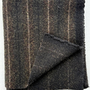 May include: A dark gray wool blanket with thin white stripes. The blanket is folded in half and the edges are frayed.
