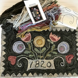 May include: A rug hooking kit featuring a floral design with a banner that reads "1820". The kit includes a pre-cut rug hooking canvas, wool yarn, and instructions.