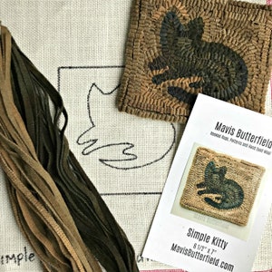 May include: A close-up of a hand-stitched hooked rug kit featuring a simple kitty design. The kit includes a canvas with a pre-printed outline, a variety of wool yarn in brown and green shades, and instructions. The kit is labeled "Simple Kitty" and is 6 1/2 inches by 7 inches.