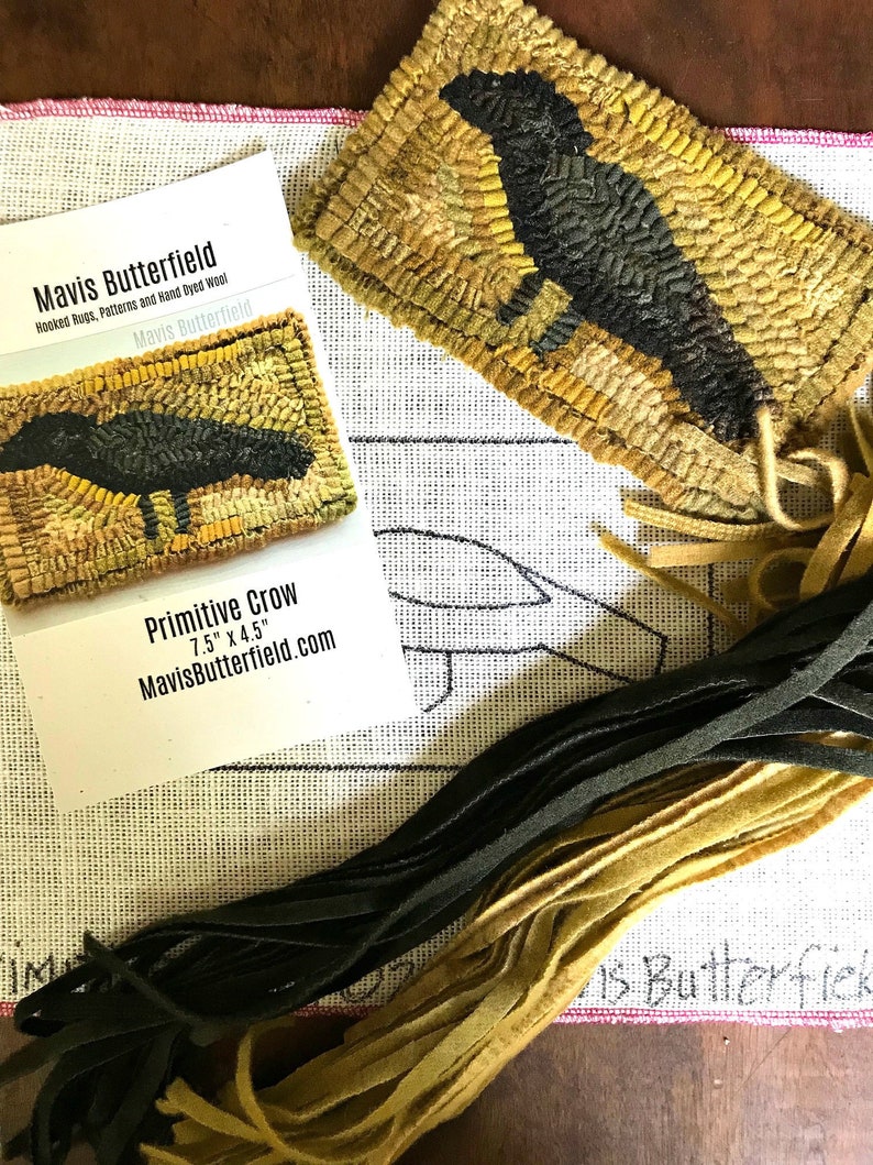 May include: A close-up of a hand-stitched wool rug depicting a primitive crow. The rug is 7.5 inches by 4.5 inches and is surrounded by strands of wool yarn in black and gold.