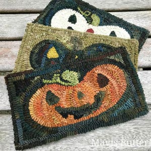 May include: Three handmade wool rug squares with Halloween themes. The top square features a white ghost with a black outline. The middle square features a green pumpkin with a black outline. The bottom square features an orange pumpkin with a black outline and a toothy grin.