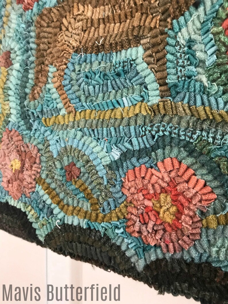 May include: A close-up of a colorful rug with a floral design. The rug is made of fabric scraps and has a variety of colors, including blue, green, brown, pink, and red. The rug is hand-stitched and has a unique, textured look.