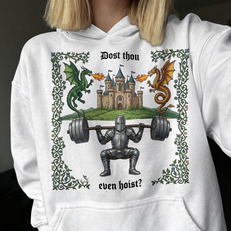 Pu&ograve; includere: Felpa con cappuccio bianca con grafica a tema medievale. Il design presenta un cavaliere che solleva pesi, affiancato da draghi, con un castello sullo sfondo. Il testo recita "Dost thou even hoist?" in un font medievale.