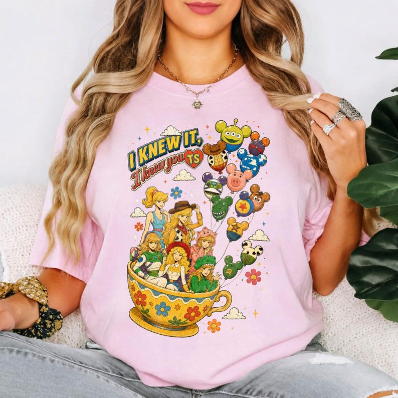 May include: A light pink t-shirt featuring a graphic print of several anime-style characters sitting in a large yellow floral teacup. Above them, a cluster of colorful character-themed balloons floats, with the text I KNEW IT, I knew you TS.