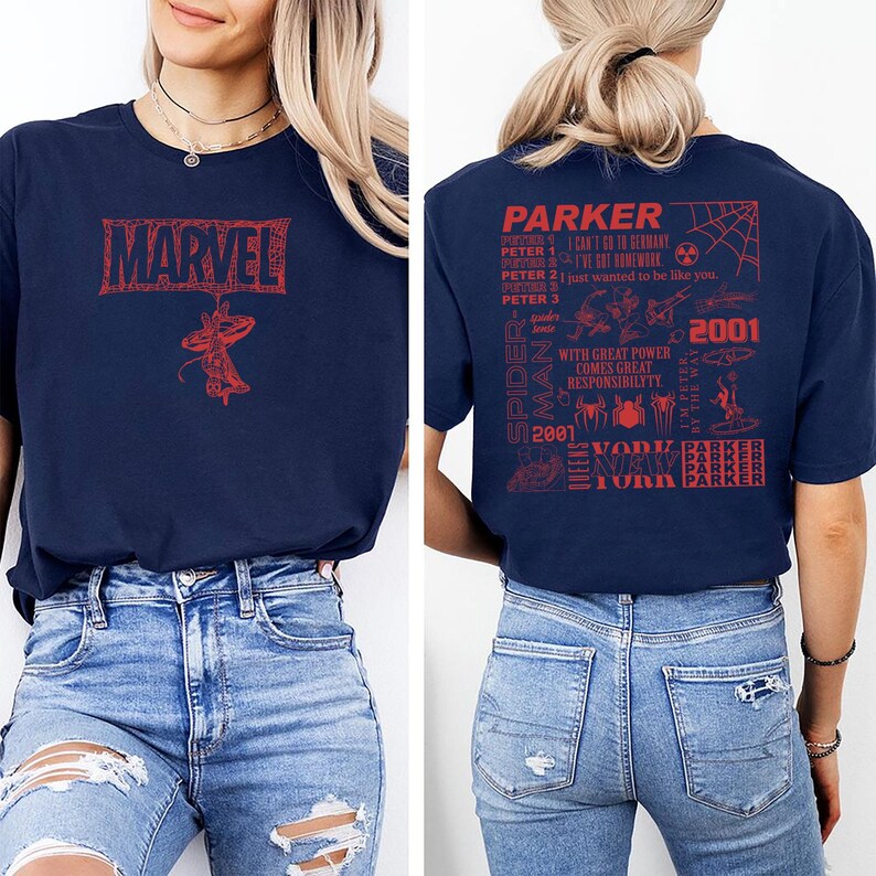 May include: Navy blue t-shirt featuring the Marvel logo and a Spider-Man graphic in red. The back of the shirt has a red graphic with text related to Spider-Man, including "Parker" and "2001". The shirt is paired with blue jeans.