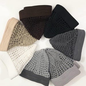 Puede incluir: Una colección de siete gorros de ganchillo dispuestos en un patrón circular. Los gorros presentan un diseño de malla abierta con una banda de tela sólida en la base, disponibles en colores blanco, beige, marrón, negro, gris oscuro, gris claro y plata.