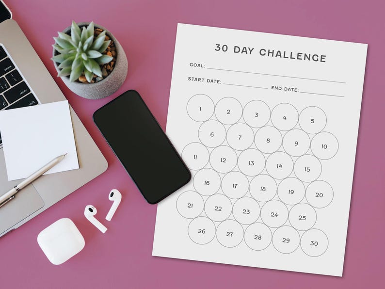 May include: A workspace scene featuring a laptop, smartphone, and a 30-day challenge tracker. The tracker has numbered circles for daily progress. A succulent plant, pen, sticky note, and wireless earbuds are also present on the pink surface.
