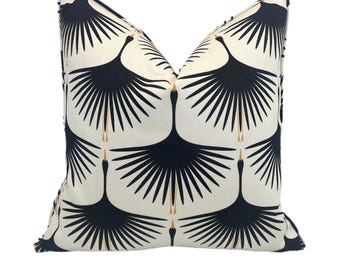 May include: A white throw pillow with a black and gold crane pattern. The cranes are stylized and have long necks and wings. The pattern is repeated across the pillow.