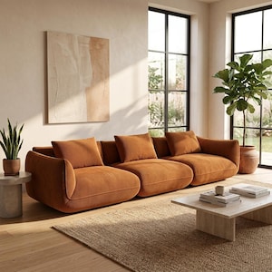 May include: A contemporary three-seater sofa upholstered in orange-brown corduroy. The sofa has curved arms and is accompanied by matching cushions. The room features a neutral colour scheme, a jute rug, and an abstract painting.
