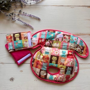 May include: A quilted cat-themed set featuring a large, curved pad with a pink border, a small square pad, and a rectangular pad. The set is made of colorful fabric squares with cat and floral patterns. The pads are on a white wooden surface.