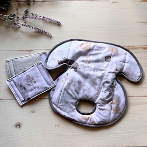 Puede incluir: Una funda para reposacabezas de asiento de coche gris y blanca con estampado de animales de safari. La funda tiene un ribete gris y un agujero en el centro para el reposacabezas.