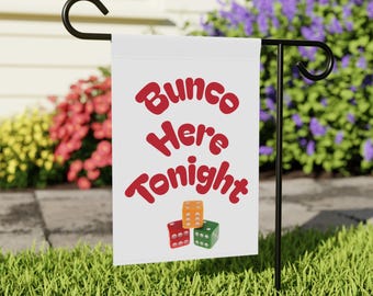 Może przedstawiać: Biała flaga ogrodowa z napisem "Bunco Here Tonight" w czerwonym skrypcie. Poniżej tekstu znajdują się trzy kostki do gry, jedna czerwona, jedna pomarańczowa i jedna zielona. Flaga jest eksponowana na czarnym metalowym stojaku w trawiastym ogrodzie.
