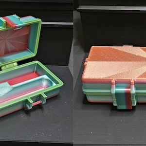 May include: A rectangular storage case with a hinged lid, featuring a gradient of green, blue, and pink. The exterior lid has a sunburst pattern in a copper-like finish. The interior contains four circular compartments and one long slot.