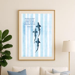 May include: Framed art print featuring three stylized blue sharks swimming on a light blue and white striped background. The print includes the text "Therefore do not worry about tomorrow... Matthew 6:34."