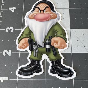 May include: A sticker featuring a cartoon character in a green uniform with black boots. The character has a white beard, a large pink nose, and an angry expression. Accessories include keys and a black holster.