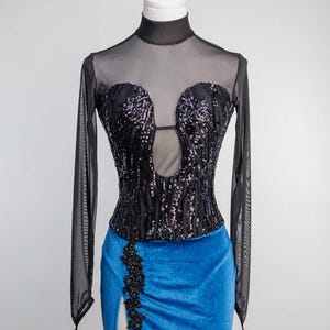 May include: A black sequined bodice with a sheer long-sleeved top and a blue velvet skirt with a side slit and black lace detail.