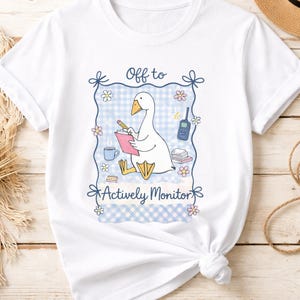 May include: A white ceramic mug with a black handle and the text "But First, Coffee" in a bold, black font. The mug is set against a neutral background, highlighting its simple design.