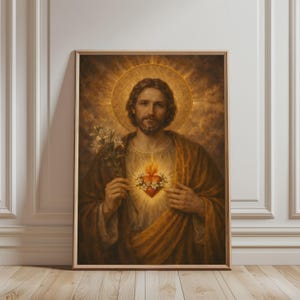 May include: Framed religious artwork featuring a portrait of a man with a halo, holding white flowers. The man has a beard and is wearing a brown robe. A glowing heart with a crown of thorns is visible on his chest. The background is a warm, golden hue.
