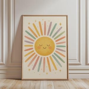 Könnte beinhalten: Ein gerahmter Wandkunstdruck mit einer zentralen gelben Sonne mit lächelndem Gesicht und rosigen Wangen. Die Sonne ist von strahlenden Strahlen in abwechselnden Pastellfarben wie Rosa, Gelb, Türkis und Lavendel umgeben, akzentuiert durch kleine goldene Sterne.