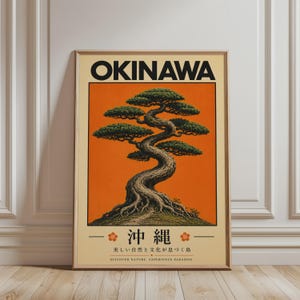 Könnte beinhalten: Gerahmter Kunstdruck mit einer stilisierten Illustration eines Bonsai-Baumes vor orangefarbenem Hintergrund. Das Wort "OKINAWA" steht oben, mit japanischem Text und dem Satz "DISCOVER NATURE. EXPERIENCE PARADISE" unten. Der Rahmen ist hellbraun.