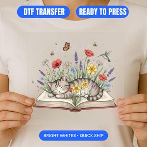 Könnte beinhalten: DTF-Transfer mit einer schlafenden grauen Tabby-Katze auf einem offenen Buch, umgeben von bunten Blumen, Schmetterlingen, Bienen und einem Kolibri. Der Text "DTF TRANSFER", "READY TO PRESS" und "BRIGHT WHITES • QUICK SHIP" sind angezeigt.