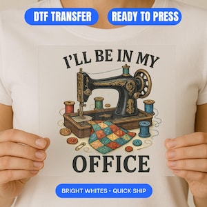 May include: A white t-shirt featuring a DTF transfer design. The design includes a vintage sewing machine, spools of thread, and the text "I'll Be In My Office". The design is surrounded by buttons, a pin, and a colorful quilt.