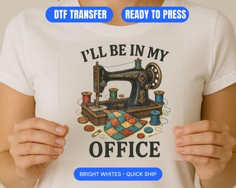 Könnte beinhalten: Ein weißes T-Shirt mit einem DTF-Transferdesign. Das Design zeigt eine Vintage-Nähmaschine, Garnrollen und den Text "I'll Be In My Office". Das Design ist von Knöpfen, einer Nadel und einem bunten Patchwork umgeben.