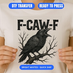 Può includere: Grafica in bianco e nero di un corvo appollaiato su un ramo, con la scritta "F-CAW-F" sopra. L'immagine è un trasferimento DTF, pronto per la stampa, con bianchi brillanti e spedizione veloce.