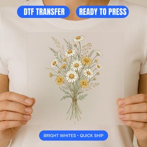 May include: A DTF transfer featuring a bouquet of daisies with yellow centers and white petals, tied with twine. The text "DTF TRANSFER", "READY TO PRESS", and "BRIGHT WHITES • QUICK SHIP" are displayed on the image.