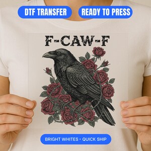 May include: A black raven illustration with the text "F-CAW-F" and surrounded by red roses. The design is a DTF transfer, ready to press, with bright whites.