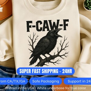 Pu&ograve; includere: Felpa color crema con un corvo nero posato su un ramo e la scritta "F-CAW-F". La stampa &egrave; realizzata su una base bianca per un colore fedele. Un capo d'abbigliamento casual.