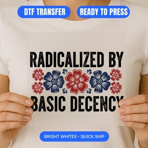 May include: A white DTF transfer featuring the text "RADICALIZED BY BASIC DECENCY" in black, with red and blue floral designs. The transfer is held up by a person wearing a white t-shirt. The image also includes the text "DTF TRANSFER", "READY TO PRESS", and "BRIGHT WHITES • QUICK SHIP".