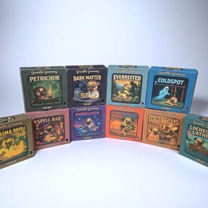 May include: A collection of square soap boxes with colorful illustrations and the words "Grumble Grooming" on them. Each box features a different design, including a pug dog, and unique names like "Petrichor" and "Dark Matter".
