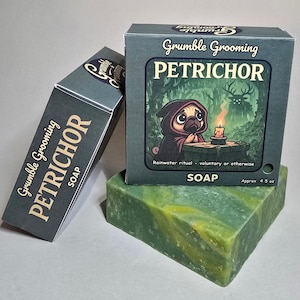 May include: A green and yellow soap bar with two boxes. The boxes are teal with the words "Grumble Grooming PETRICHOR SOAP" and a cartoon pug in a cloak. The box reads "Rainwater ritual - voluntary or otherwise" and "Approx 4.5 oz."