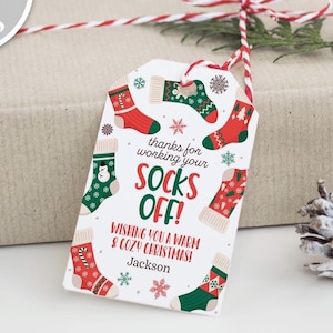 May include: A white gift tag with a red and green Christmas sock pattern. The tag says "thanks for working your socks off! Wishing you a warm & cozy Christmas!" with the name "Jackson" at the bottom.