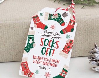 May include: A white gift tag with a red and green Christmas sock pattern. The tag says "thanks for working your socks off! Wishing you a warm & cozy Christmas!" with the name "Jackson" at the bottom.