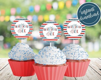 Puede incluir: Tres adornos para cupcakes rojo, blanco y azul con el texto "Our Little Firecracker is Turning One" y un gráfico de fuegos artificiales.